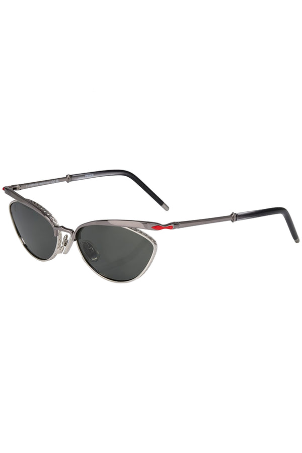 Rotated view of Christian Louboutin sunglasses in gray with metal frame and red details, shown against a plaid white background.