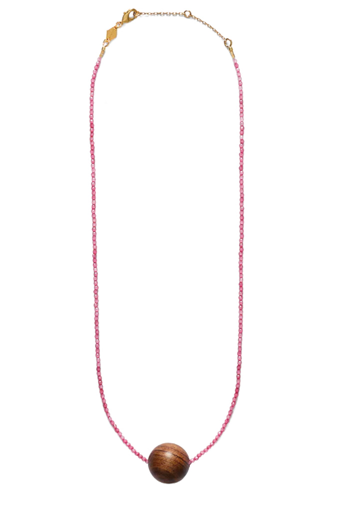 A delicate pink beaded necklace with a central round wooden bead pendant and gold-tone chain hardware, shown against a plain white background.