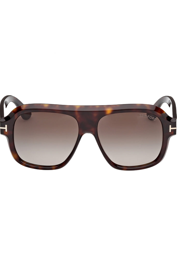 Tom Ford mask sunglasses in brown with tortoiseshell frame and metal T details, shown against a plaid white background