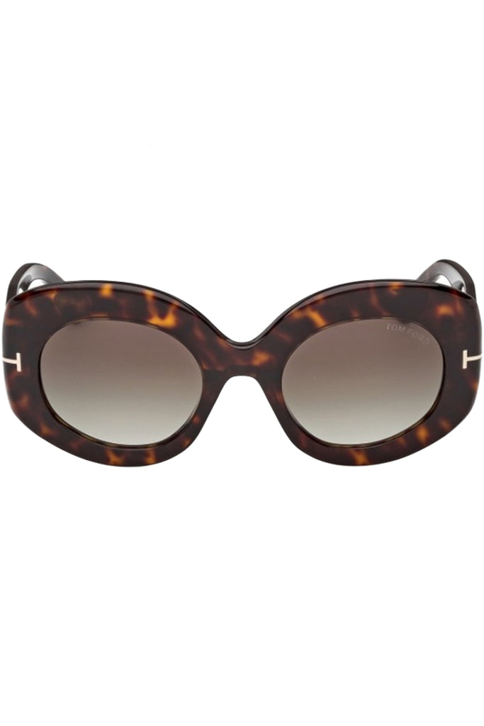 Tom Ford oval sunglasses in brown with dark tortoise frame and metal T details, shown against a plaid white background.