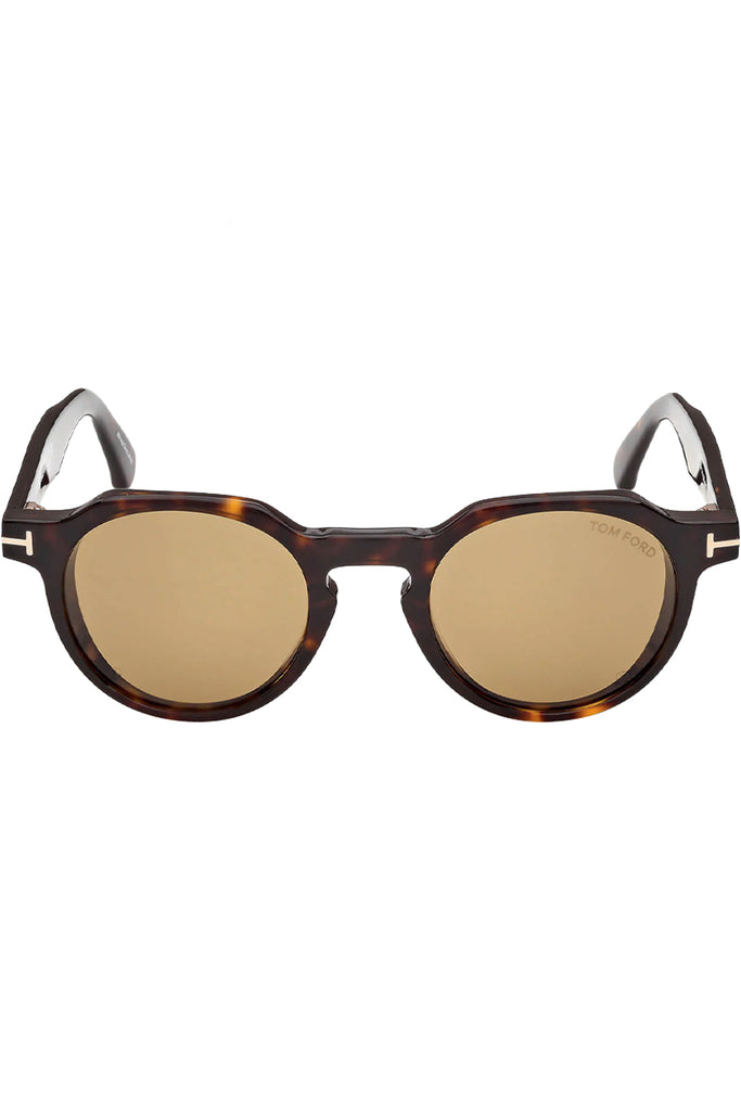 Tom Ford oval sunglasses in yellow with dark tortoise frame and gold T details, shown against a plaid white background.