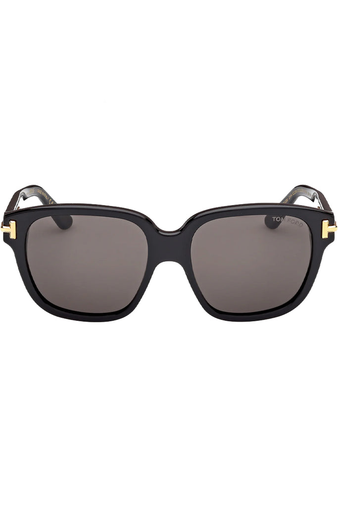 Tom Ford butterfly sunglasses in gray with black frame and gold T details, shown against a plaid white background.