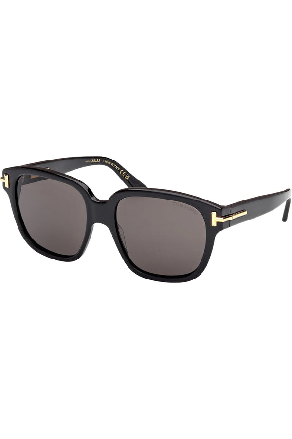 Rotated view of Tom Ford butterfly sunglasses in gray with black frame and gold T details, shown against a plaid white background.