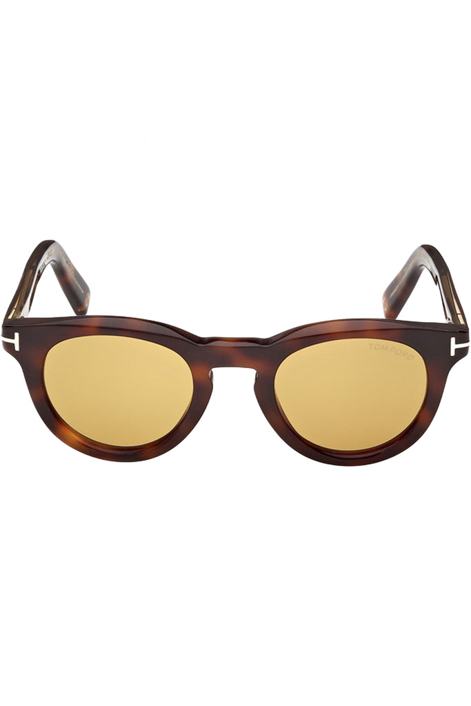 Tom Ford round sunglasses in yellow with tortoise frame and metal T details, shown against a plaid white background.