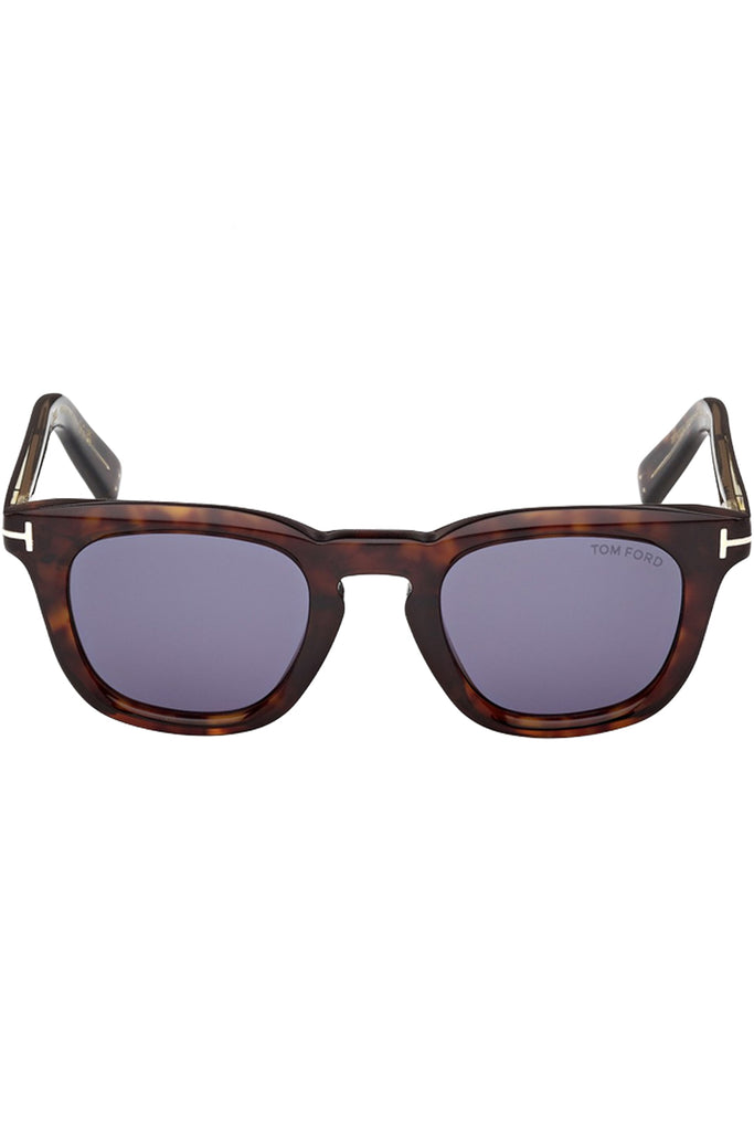 Tom Ford sunglasses in blue with tortoise frame and metal T details, shown against a plaid white background.