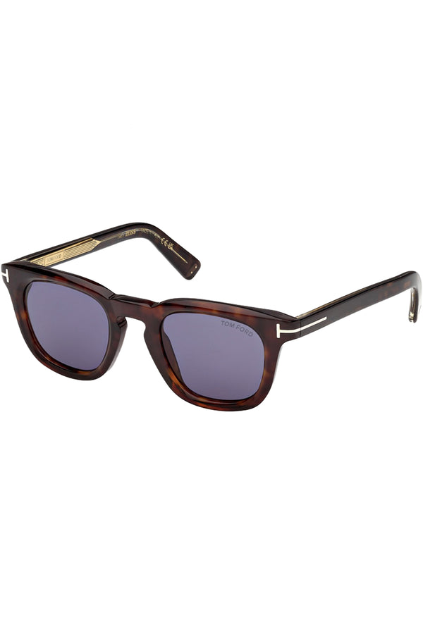 Rotated view of Tom Ford sunglasses in blue with tortoise frame and metal T details, shown against a plaid white background.