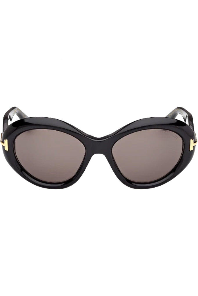 Tom Ford oval sunglasses in gray with black frame and gold T details, shown against a plaid white background.