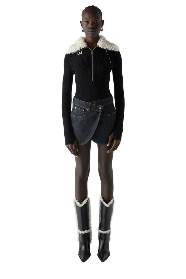 Model wearing the fold-over denim mini skirt in dark navy color from the brand COPERNI