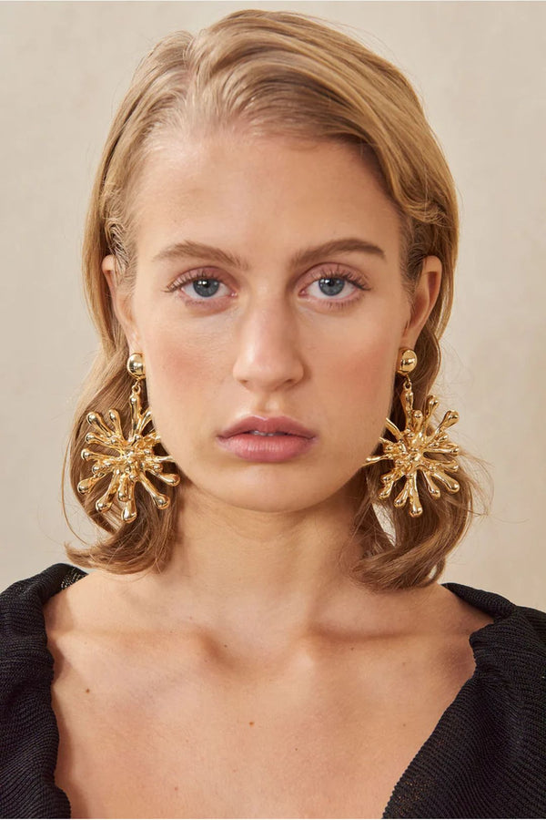 Model wearing the Odeya starburst earrings in gold color from the brand CULT GAIA