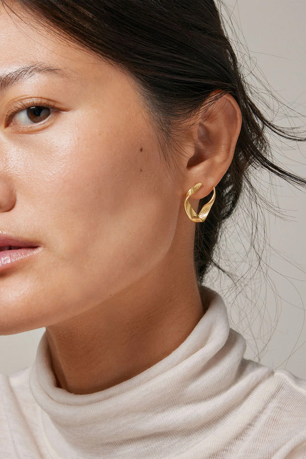Model wearing the Dalia earrings in gold colour from the brand ENAMEL COPENHAGEN