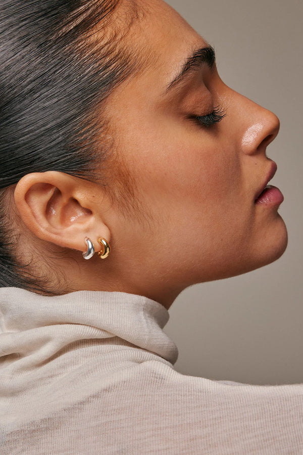 Model wearing the Gianna small hoop earrings in gold colour from the brand ENAMEL COPENHAGEN