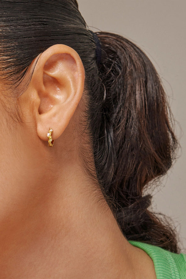 Model wearing the Laia hoop earrings in gold and multicolor from the brand ENAMEL COPENHAGEN