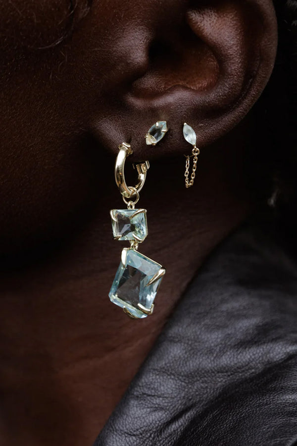 Model wearing the claw double drop earrings in gold and aquamarine colour from the brand F+H JEWELLERY