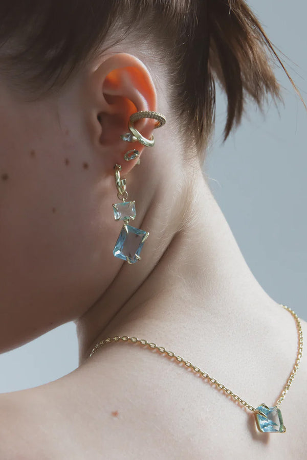 Model wearing the marquise ear cuff in gold and aquamarine colour from the brand F+H JEWELLERY