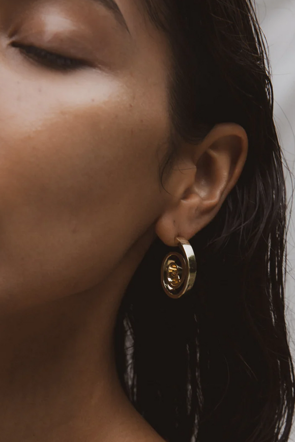 Model wearing the Sprial Shell earrings in gold colour from the brand F+H JEWELLERY.