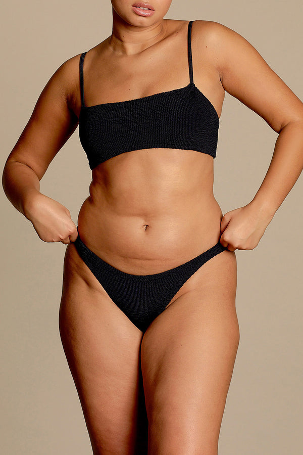 Model wearing the Gigi spaghetti-strap bikini in black color from the brand HUNZA G