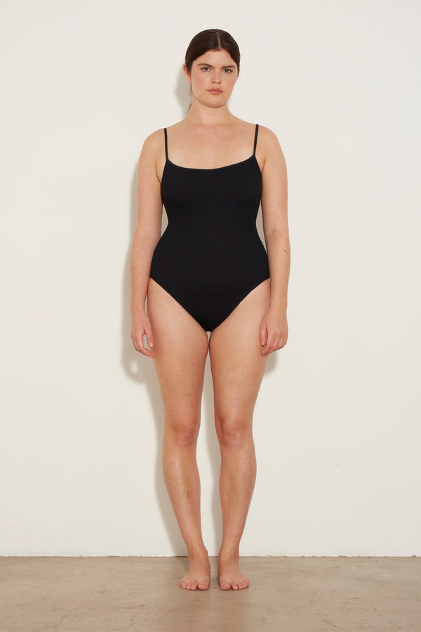Model wearing the Pamela spaghetti-strap swimsuit in black color from the brand HUNZA G