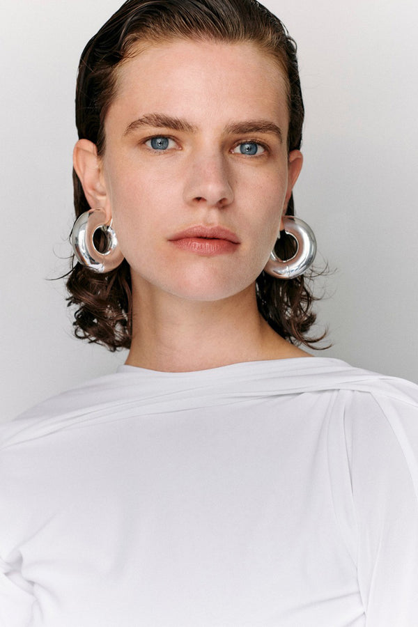 Model wearing the large Strato hoop earrings in silver colour from the brand UNCOMMON MATTERS